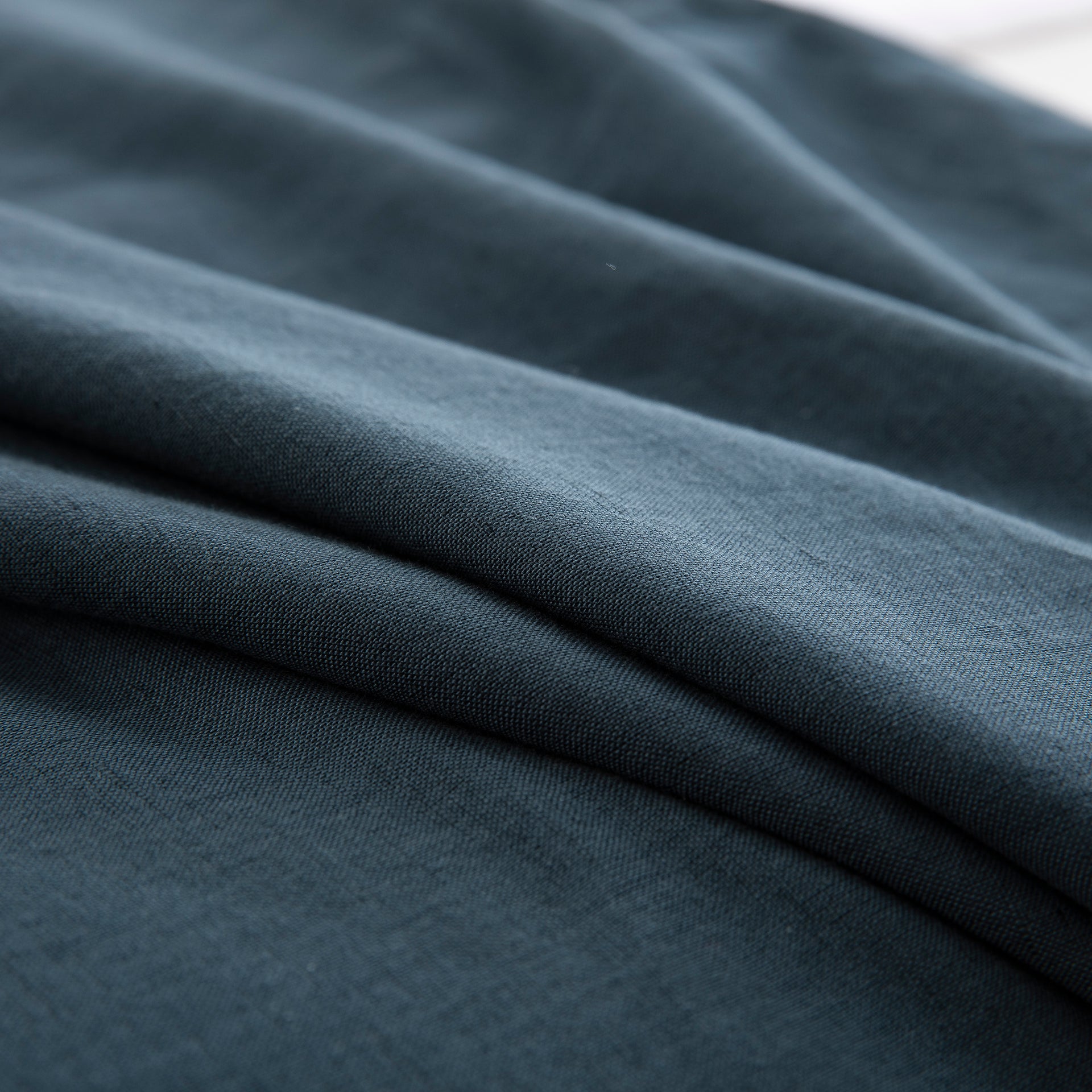 Close-up of the calming blue-grey tone and soft texture of the midnight slate blue linen cotton blend - DAUAOTO