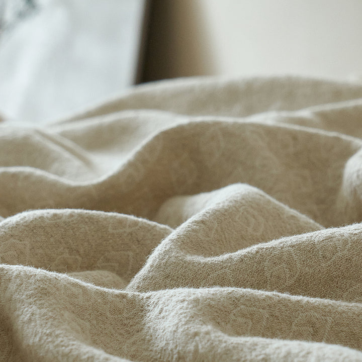 Detailed view of the natural crinkle finish and soft folds on the oatmeal beige linen blend blanket.