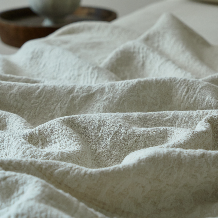 Close-up of the breathable natural ivory linen blend fabric showing its natural crinkle texture.