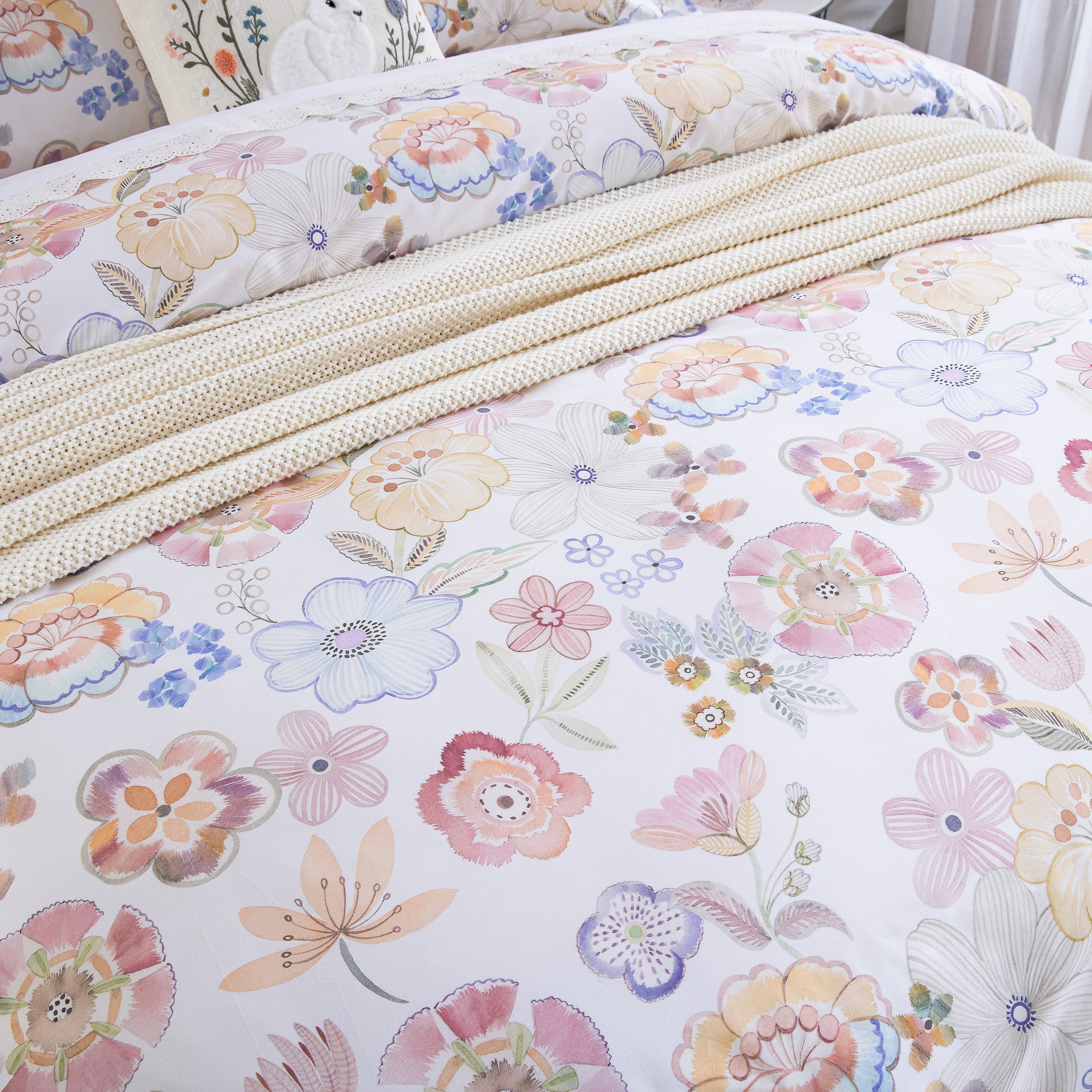 DAUAOTO pastel watercolor floral duvet cover layered elegantly with a cozy cream knit throw blanket.