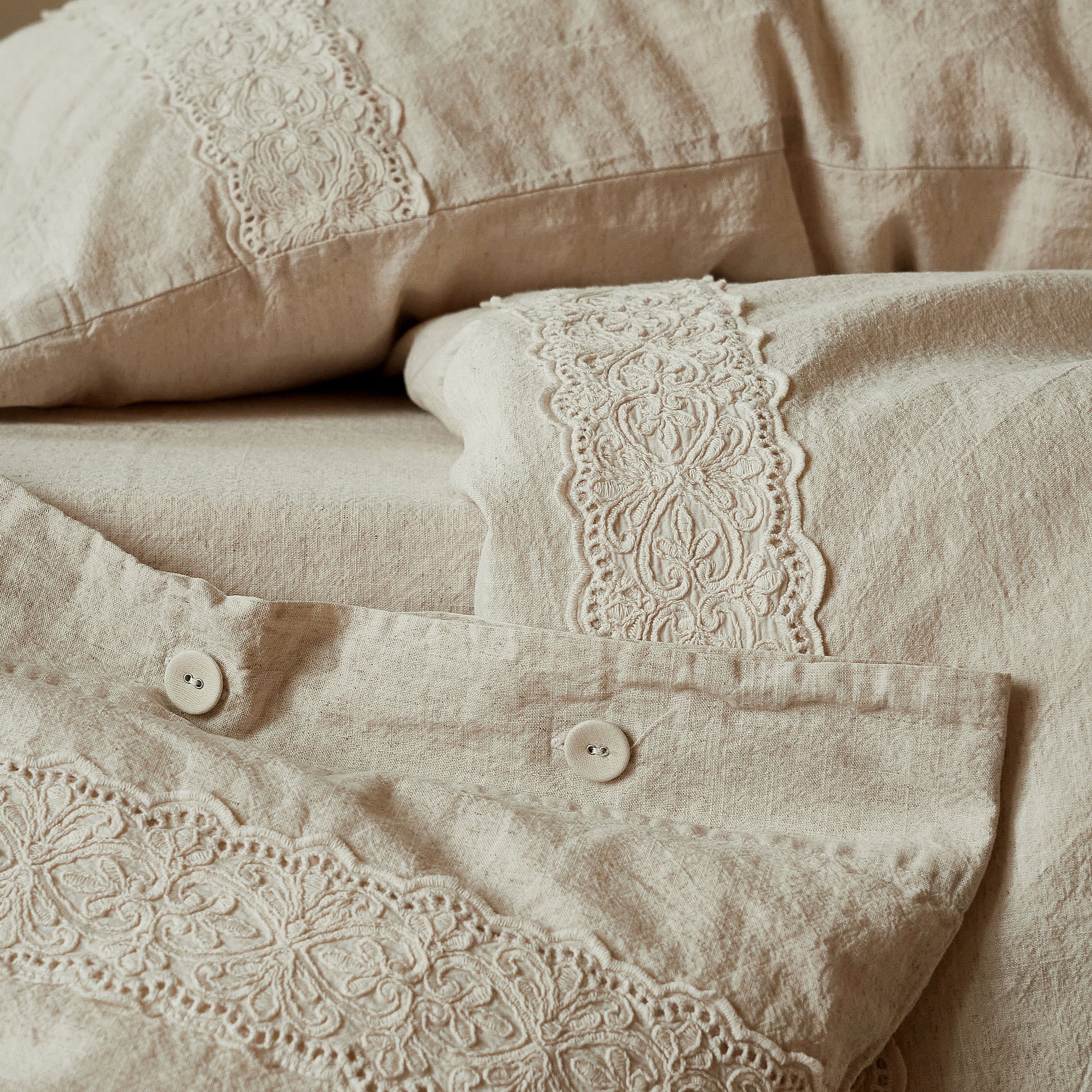 Close up of rustic buttons and 3D floral embroidered lace on the DAUAOTO Provence linen duvet cover.