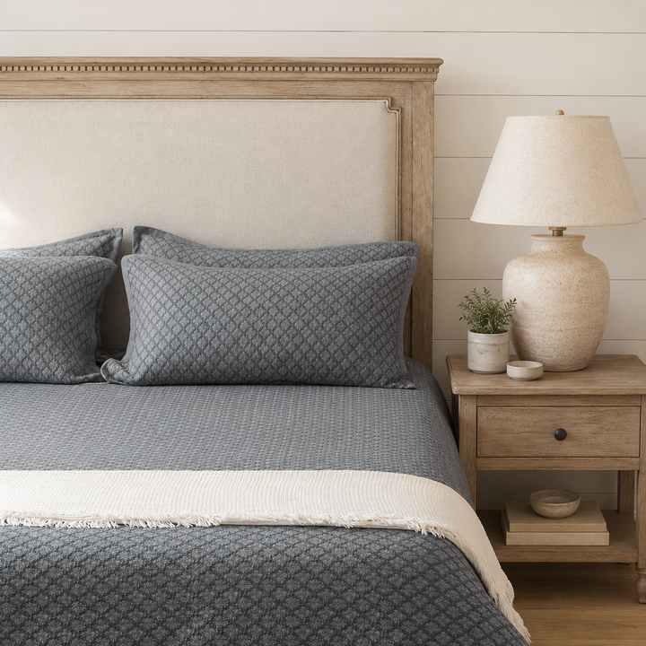 Slate blue diamond jacquard coverlet layered over a light sheet with matching pillow shams