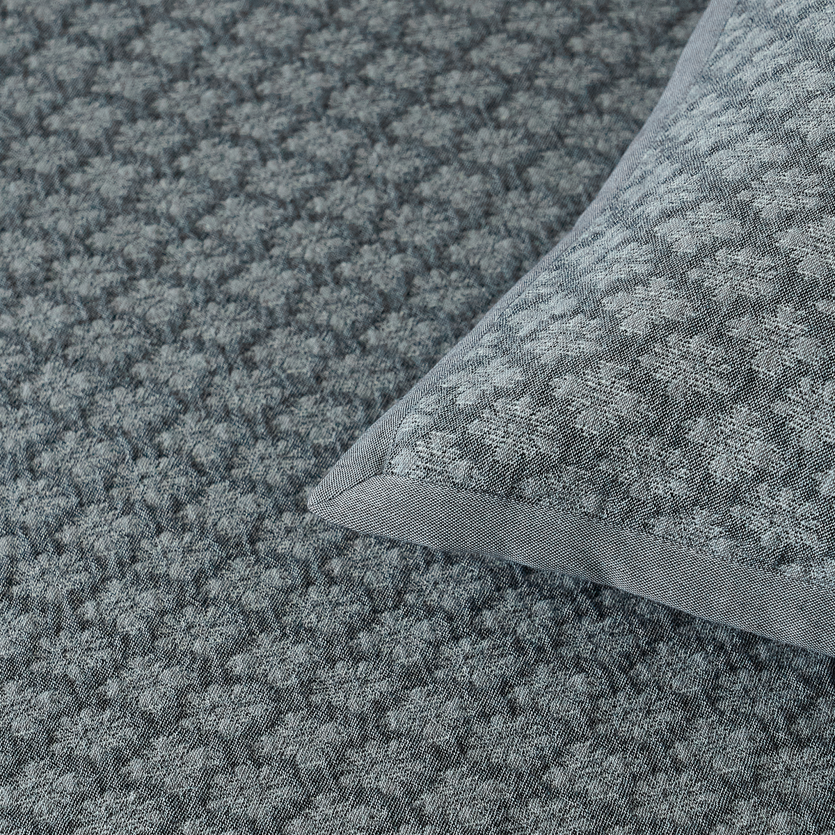 Detailed view of the slate blue diamond jacquard coverlet corner and finished border