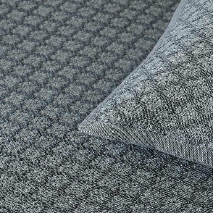 Detailed view of the slate blue diamond jacquard coverlet corner and finished border