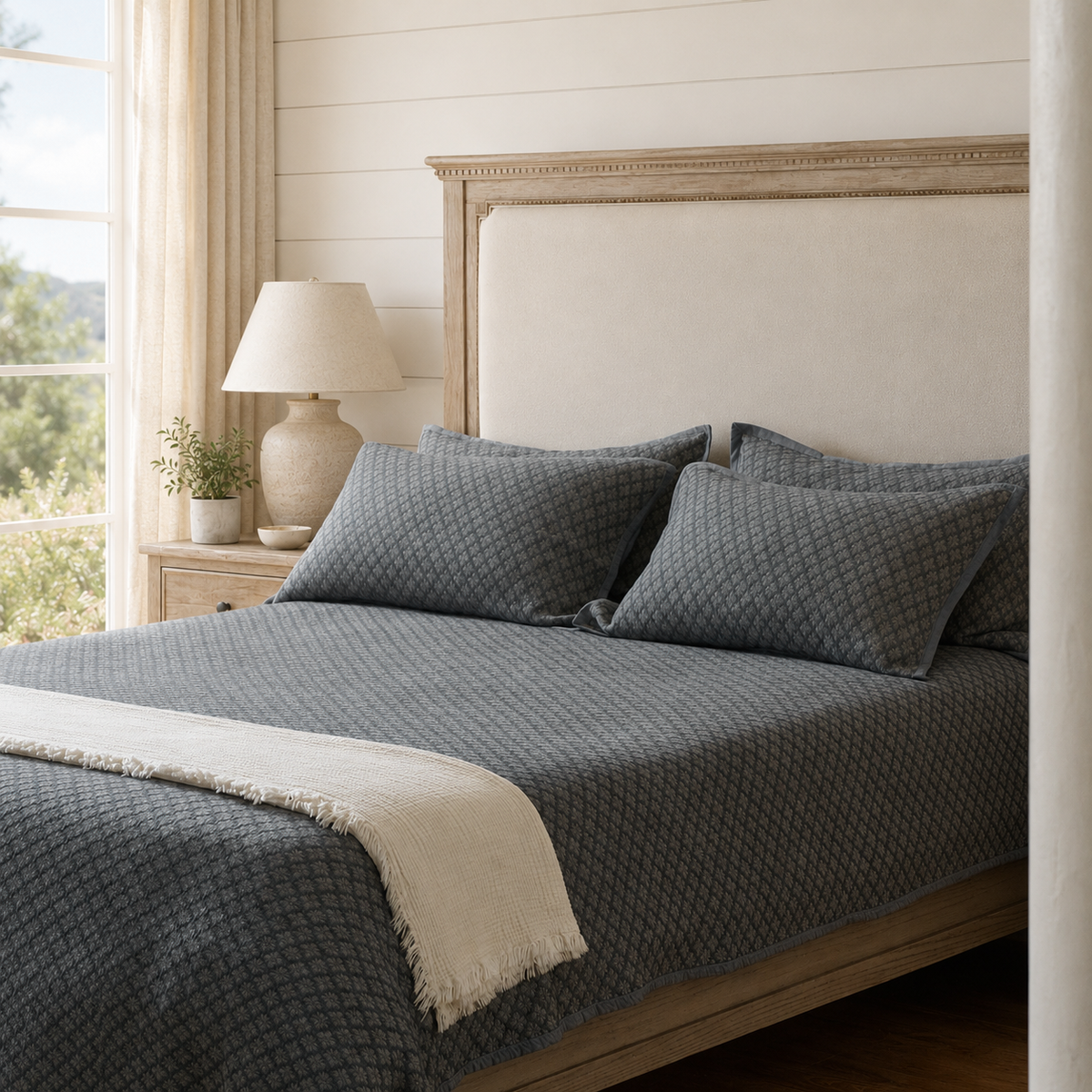 Slate blue washed cotton jacquard coverlet styled in a relaxed neutral bedroom
