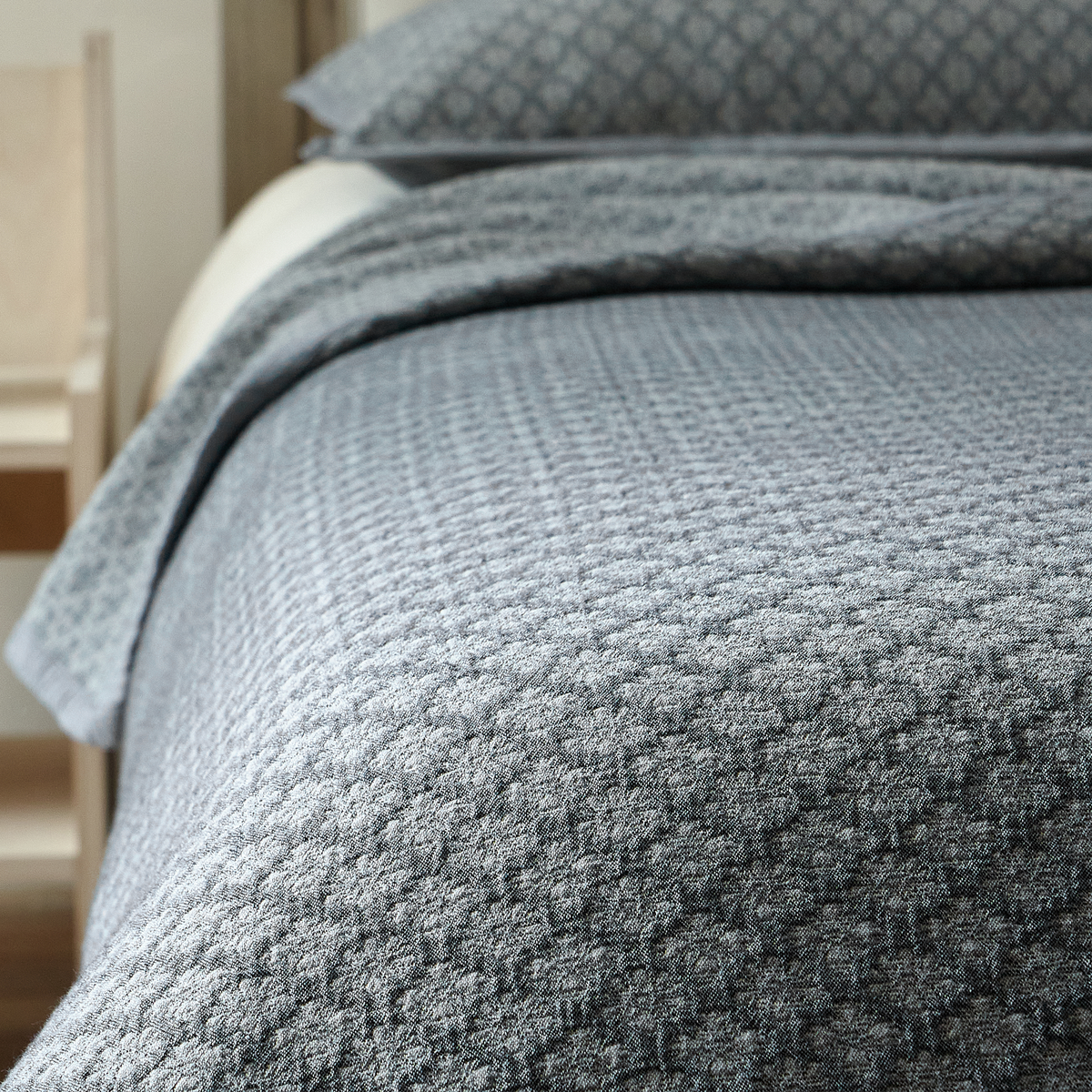 Close-up of slate blue washed cotton coverlet showing the raised diamond jacquard texture