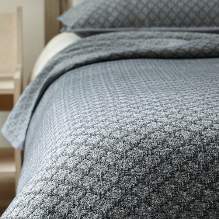 Close-up of slate blue washed cotton coverlet showing the raised diamond jacquard texture