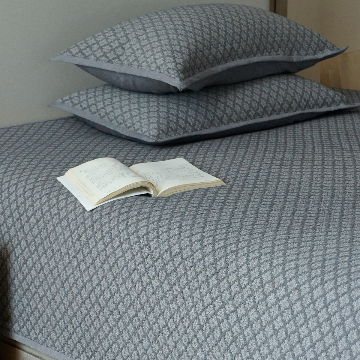 Pair of slate blue diamond jacquard pillow shams styled with the matching cotton coverlet