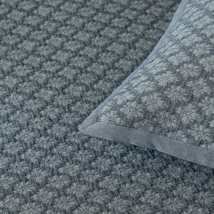 Close-up of the tailored corner detailing on the slate blue diamond jacquard pillow sham.