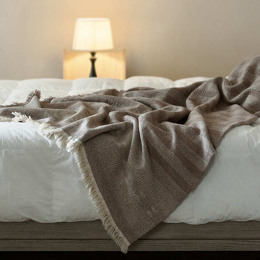 Large taupe brown striped cotton-linen throw used as a summer bedspread on a white bed.