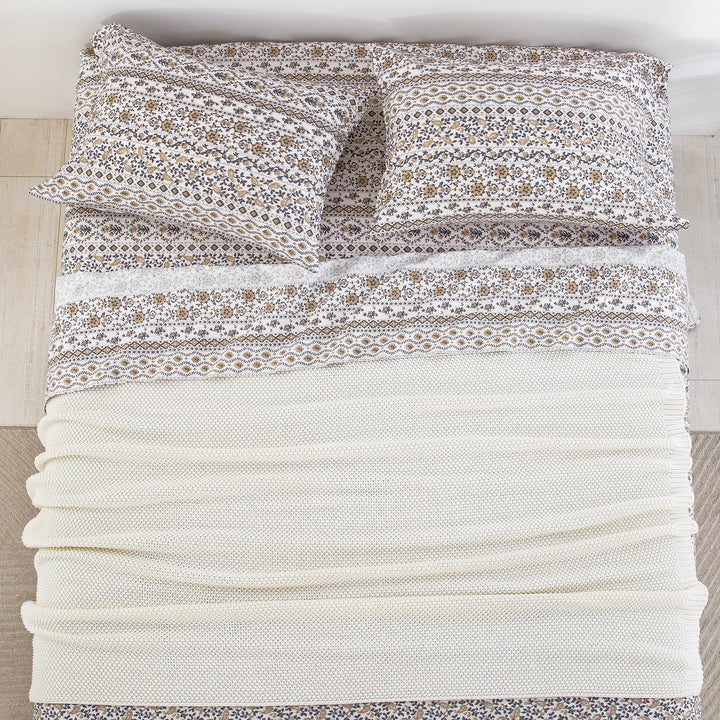 Top-down bird's-eye view of a neatly made bed featuring the DAUAOTO earthy block print sheet set layered with a cream blanket.