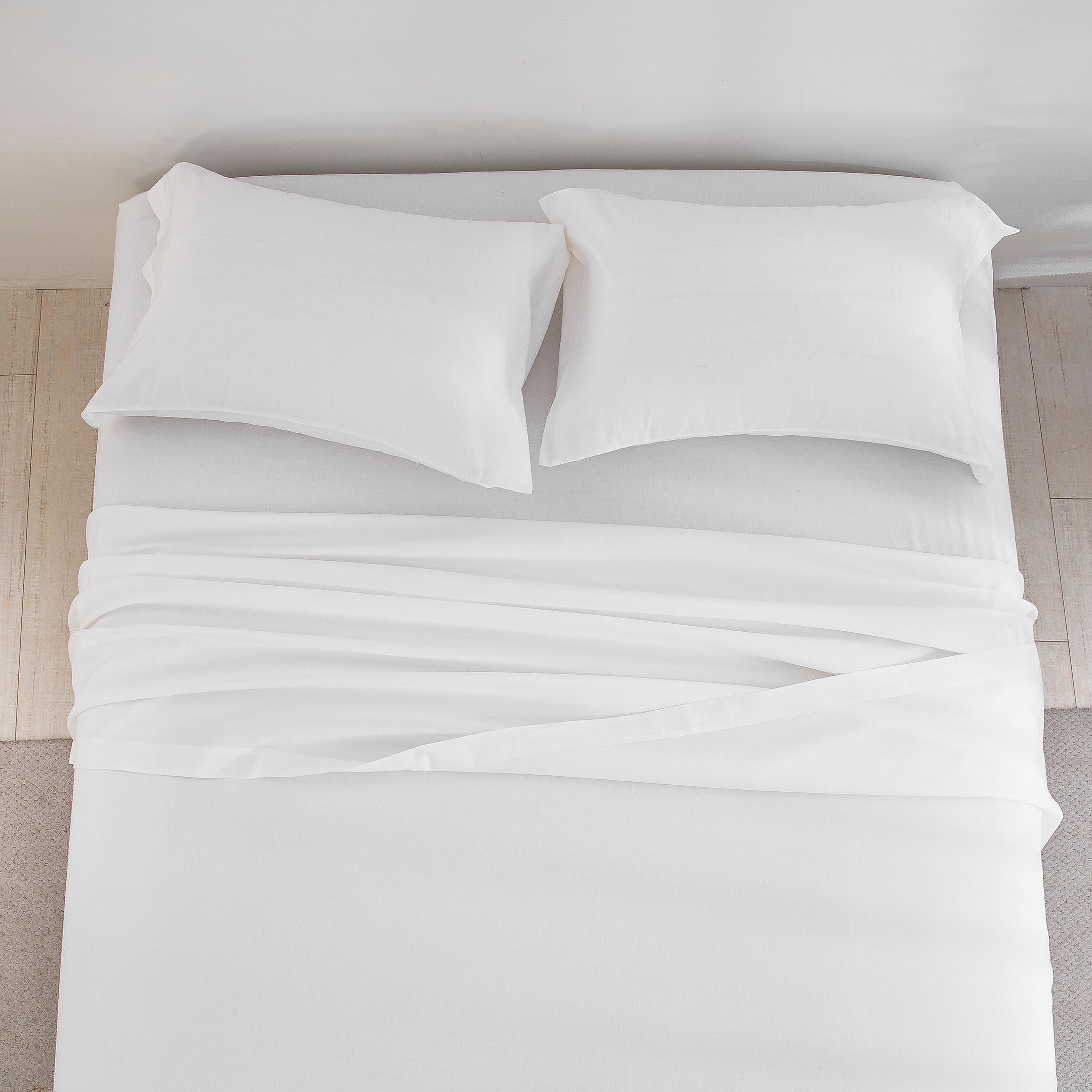 Top-down view of the pristine elegance and clean white hue of the prewashed linen cotton bed sheets - DAUAOTO