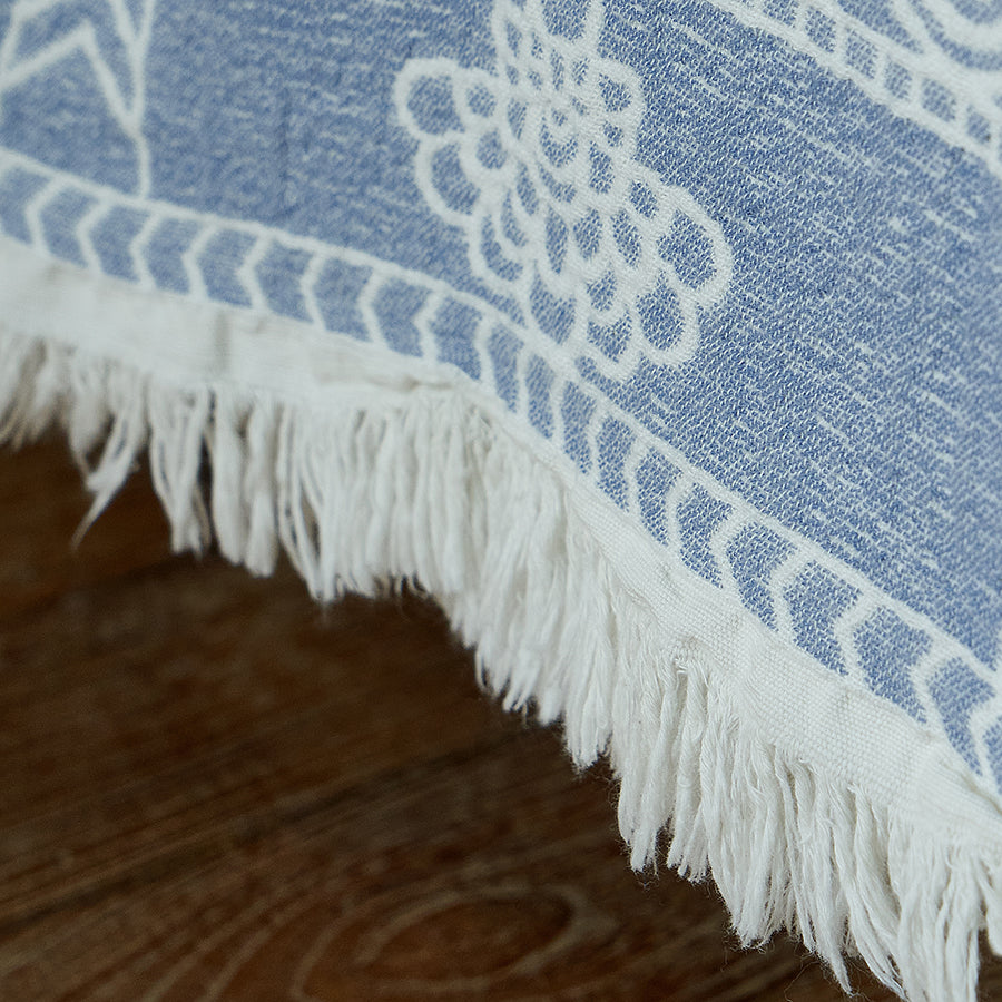 Close-up of the vintage jacquard woven border pattern and delicate fringe on the blue throw.