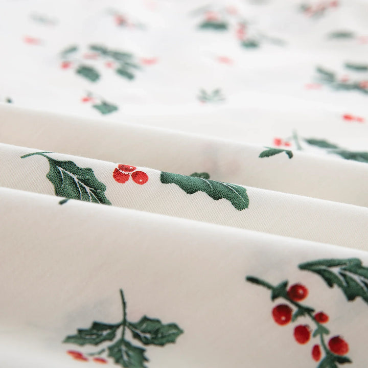 Close-up of the vintage-inspired green holly leaves and vibrant red berries print on warm ivory pure cotton fabric - DAUAOTO